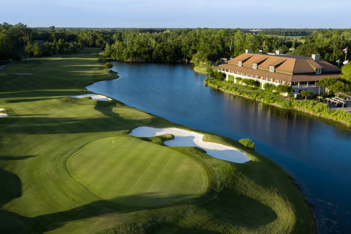 A panoramic view of a lush golf course, complete with a reflective water feature and a welcoming clubhouse in the background. The scene is set under a soft sunset, capturing the relaxed atmosphere and social potential of the greens.