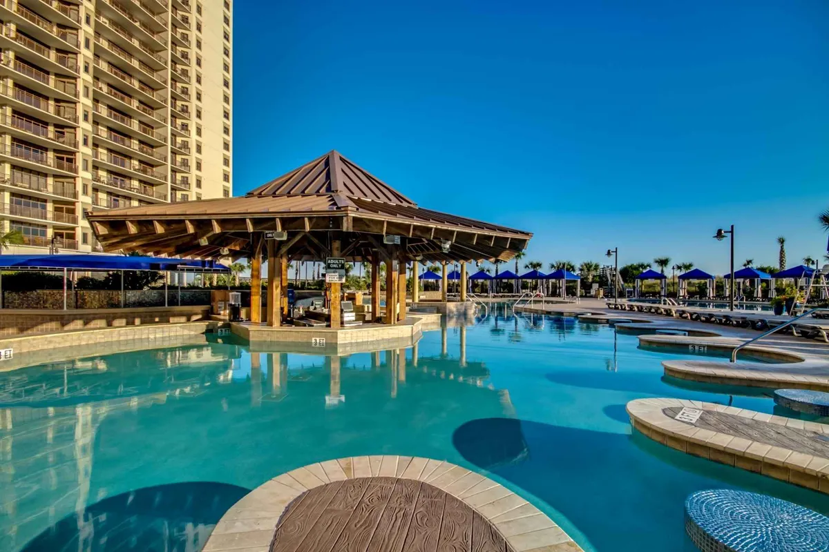 An inviting pool area with a stylish cabana and rows of lounge chairs. The tranquil water reflects the sky, and the setting feels private yet luxurious—ideal for unwinding or enjoying poolside gatherings. The cabana hints at exclusive guest experiences and comfort.